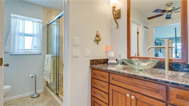 bathroom with toilet, a shower with shower door, vanity, ceiling fan, and tile patterned flooring