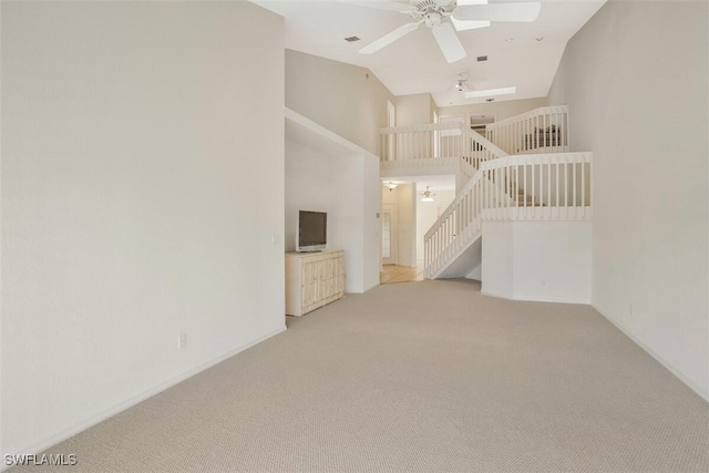 unfurnished living room featuring a towering ceiling, light colored carpet, and ceiling fan