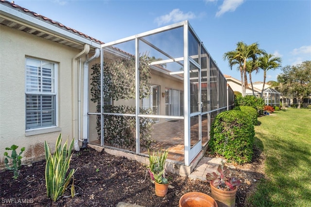 view of property exterior with glass enclosure and a lawn