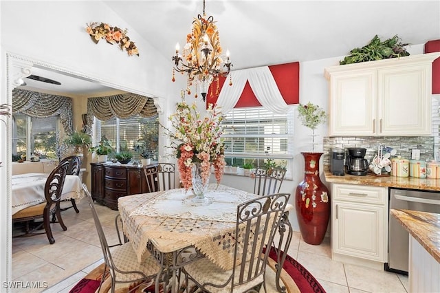 tiled dining area with lofted ceiling and a notable chandelier