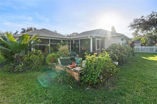 rear view of property with a sunroom and a yard