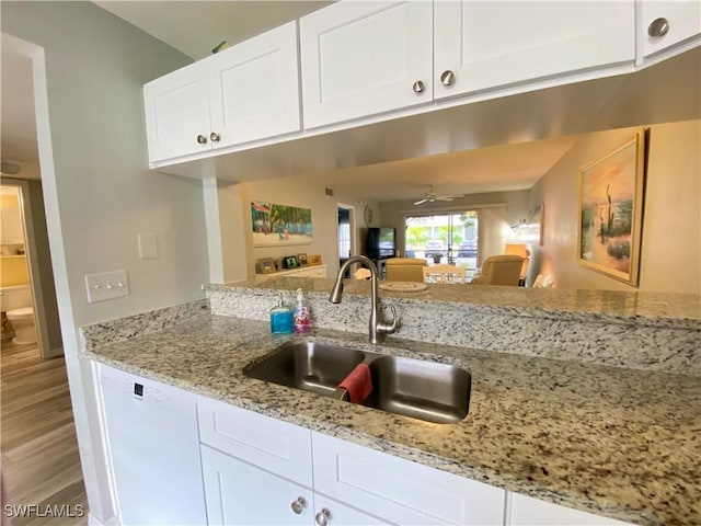 kitchen with sink, white cabinets, ceiling fan, light stone counters, and white dishwasher