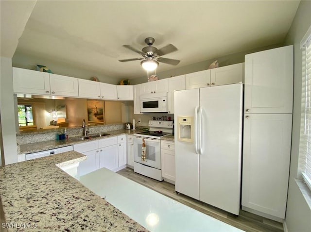 kitchen featuring white cabinetry, white appliances, light stone countertops, and sink