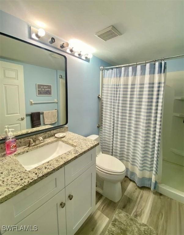 bathroom featuring walk in shower, vanity, toilet, and hardwood / wood-style floors