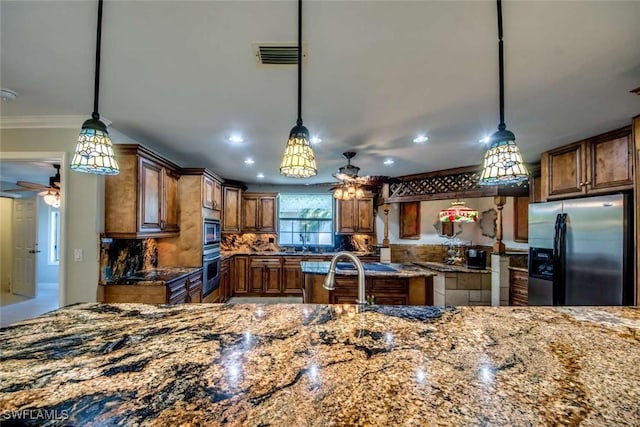 kitchen with dark stone countertops, decorative backsplash, stainless steel appliances, and decorative light fixtures