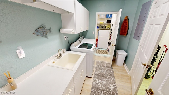 laundry area featuring cabinets, light hardwood / wood-style flooring, washer and clothes dryer, and sink