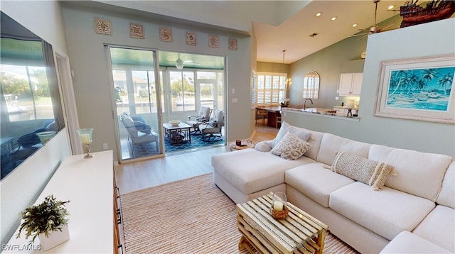 living room featuring ceiling fan, light hardwood / wood-style floors, sink, and vaulted ceiling