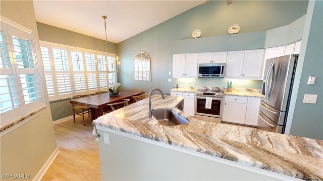 kitchen with white cabinets, sink, light stone countertops, and stainless steel appliances