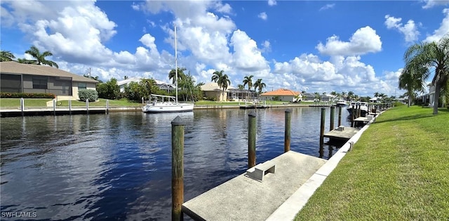 view of dock with a lawn and a water view