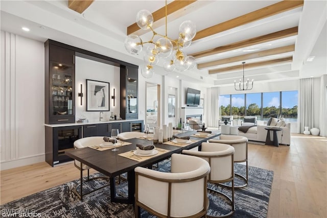 dining space featuring beamed ceiling, light hardwood / wood-style floors, and an inviting chandelier