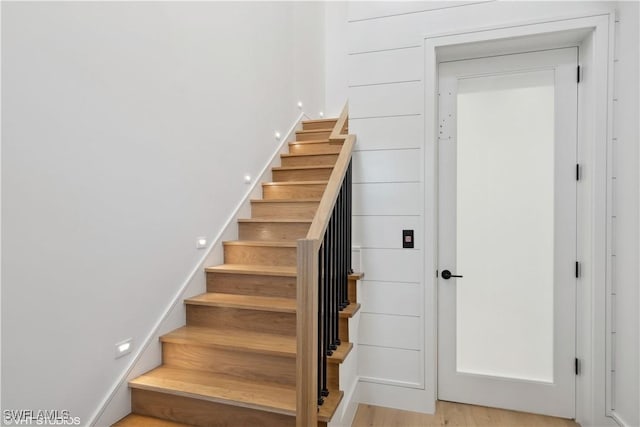 staircase with hardwood / wood-style flooring and wooden walls