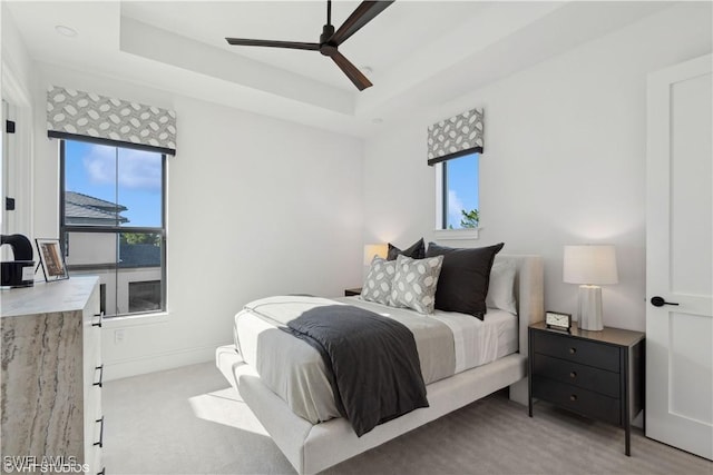 bedroom featuring a tray ceiling, multiple windows, and ceiling fan