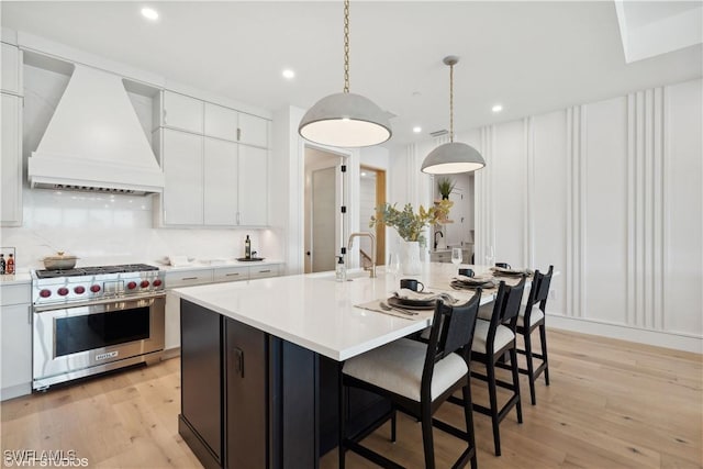 kitchen featuring white cabinets, custom range hood, and premium range