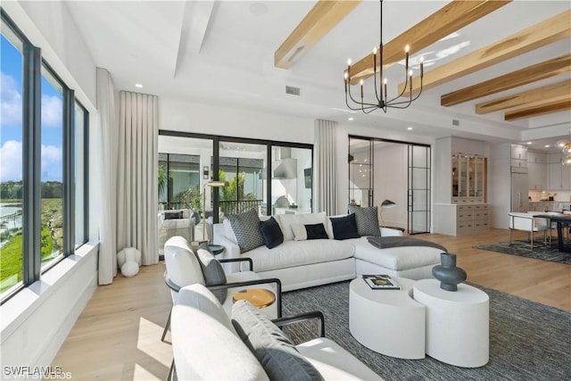 living room featuring beamed ceiling, a chandelier, light hardwood / wood-style flooring, and plenty of natural light