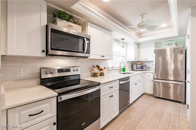 kitchen with white cabinets, stainless steel appliances, a raised ceiling, and sink