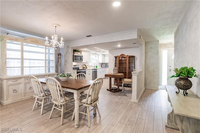 dining area featuring a wealth of natural light, a chandelier, and light hardwood / wood-style floors