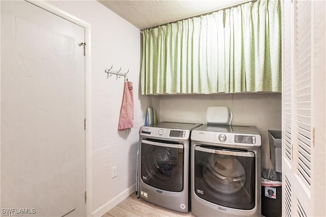 clothes washing area featuring washer and dryer and light hardwood / wood-style floors