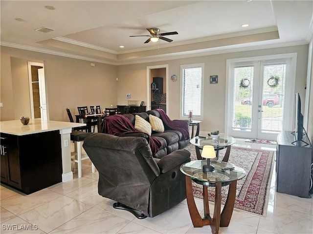 living room featuring a tray ceiling, crown molding, and french doors