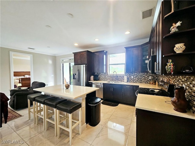 kitchen with sink, a breakfast bar area, decorative backsplash, a kitchen island, and stainless steel appliances