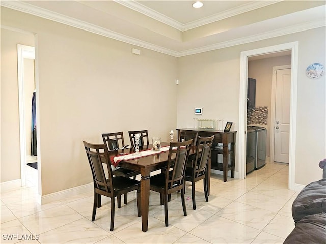 dining area featuring a tray ceiling, ornamental molding, and independent washer and dryer