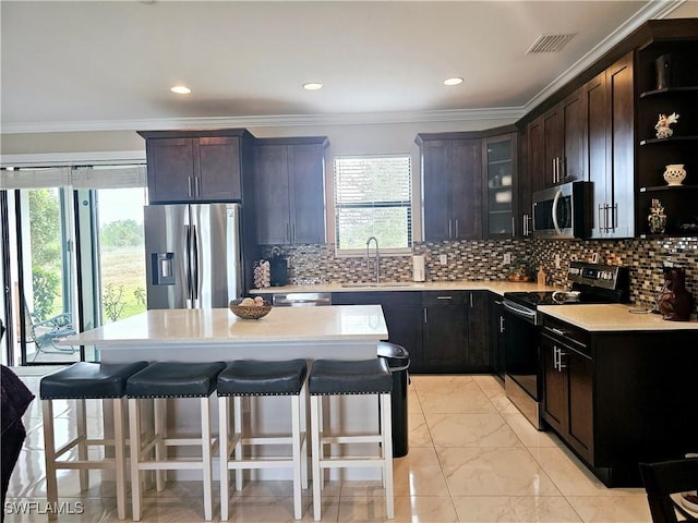 kitchen with appliances with stainless steel finishes, a breakfast bar, dark brown cabinets, sink, and a kitchen island