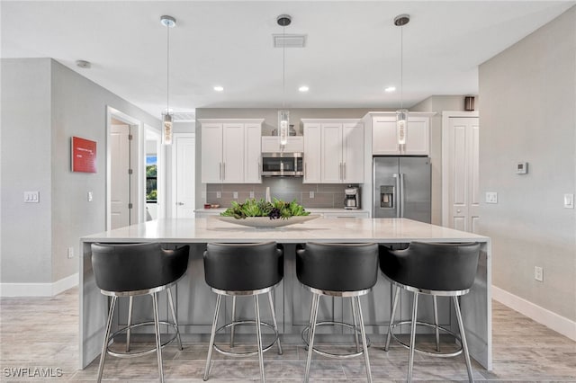 kitchen featuring white cabinets, decorative backsplash, stainless steel appliances, and a spacious island