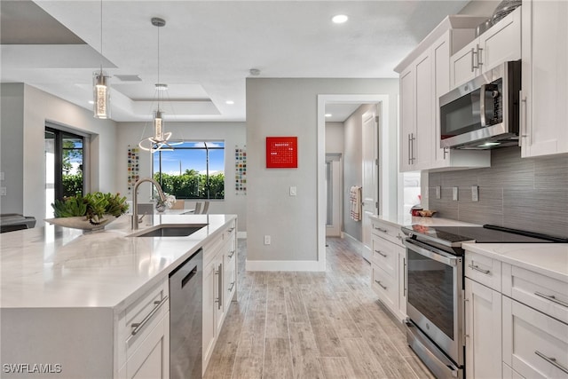 kitchen featuring decorative backsplash, stainless steel appliances, sink, decorative light fixtures, and white cabinetry