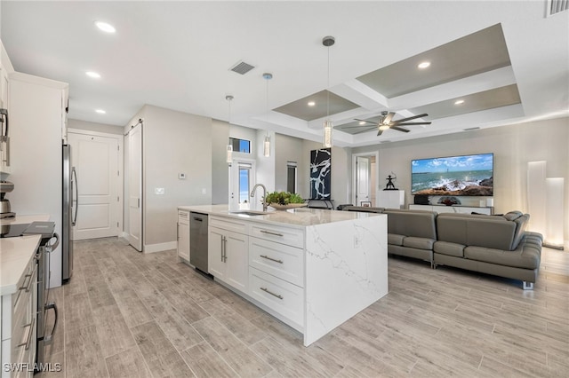 kitchen featuring a center island with sink, white cabinetry, stainless steel appliances, and ceiling fan