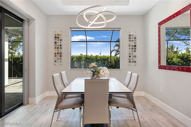 dining area with an inviting chandelier, a wealth of natural light, and light hardwood / wood-style flooring