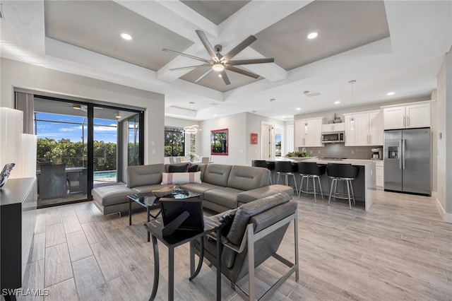 living room featuring coffered ceiling, ceiling fan, and a tray ceiling