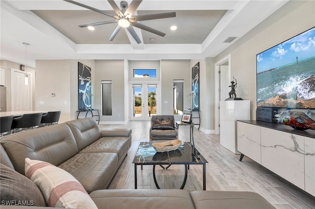 living room with french doors, light wood-type flooring, a tray ceiling, and ceiling fan