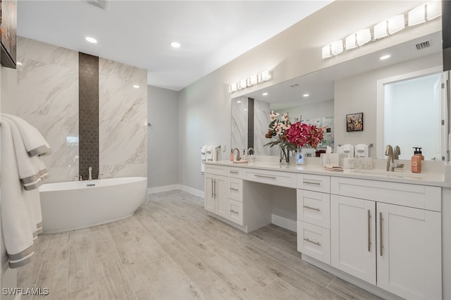 bathroom featuring a washtub, vanity, hardwood / wood-style flooring, and tile walls