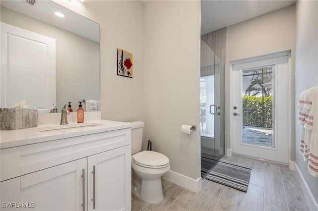 bathroom with vanity, toilet, and a shower with door