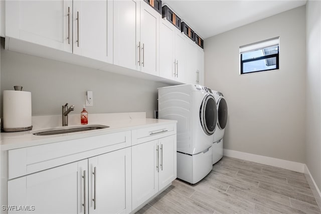 laundry area with cabinets, washing machine and dryer, and sink