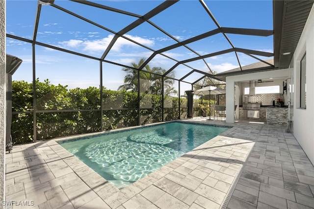 view of pool featuring an outdoor kitchen, glass enclosure, a patio, and a grill