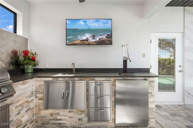 bar featuring stainless steel refrigerator and sink