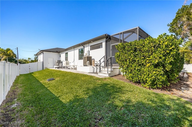 rear view of property with a patio area, a lanai, and a lawn