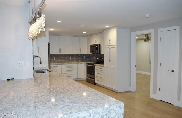 kitchen with white cabinetry, electric range, sink, and light stone counters