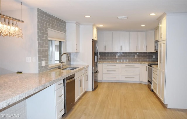 kitchen with decorative backsplash, stainless steel appliances, sink, light hardwood / wood-style floors, and white cabinetry