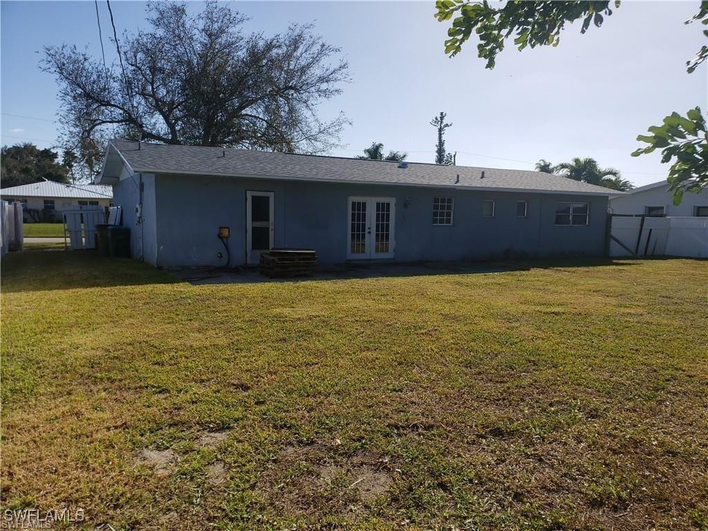 rear view of property with a lawn and french doors