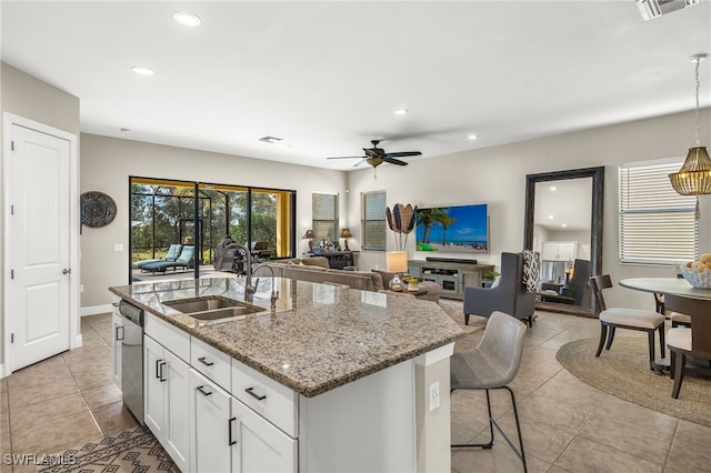 kitchen featuring light stone countertops, ceiling fan, sink, a center island with sink, and white cabinetry