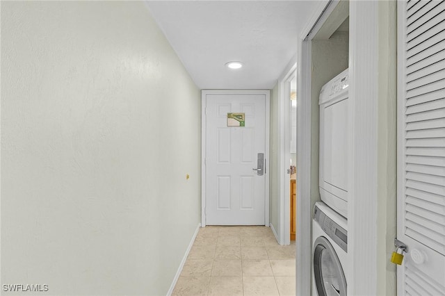 laundry area with light tile patterned floors and stacked washer and dryer