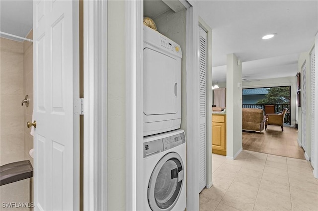 laundry area with ceiling fan, light tile patterned floors, and stacked washer and dryer