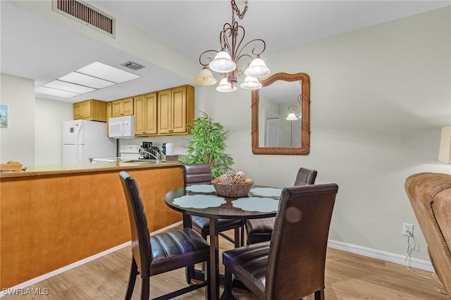 dining room featuring light hardwood / wood-style flooring, a notable chandelier, and sink