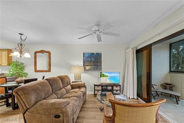 living room featuring ceiling fan with notable chandelier and light wood-type flooring