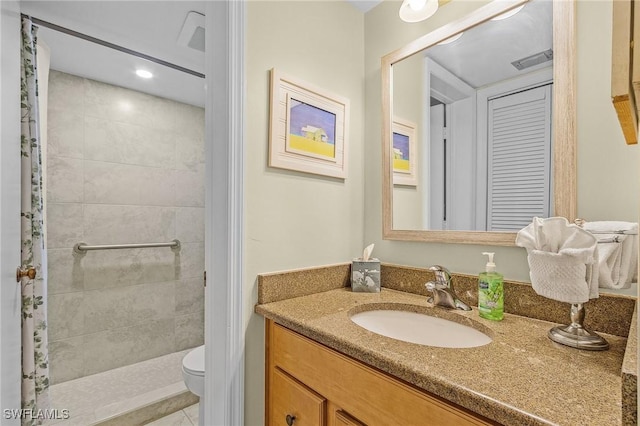 bathroom featuring tile patterned flooring, a tile shower, vanity, and toilet