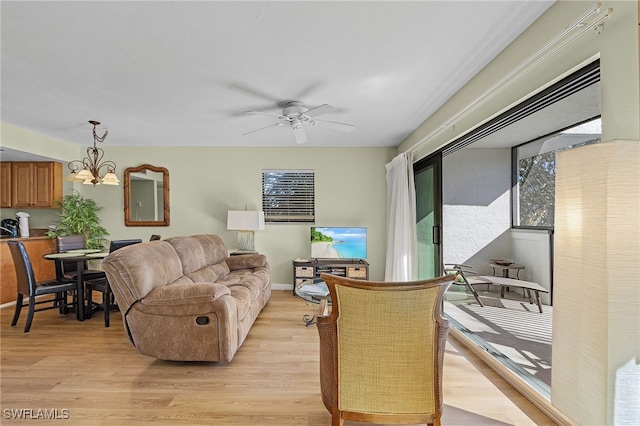 living room with ceiling fan with notable chandelier and light wood-type flooring