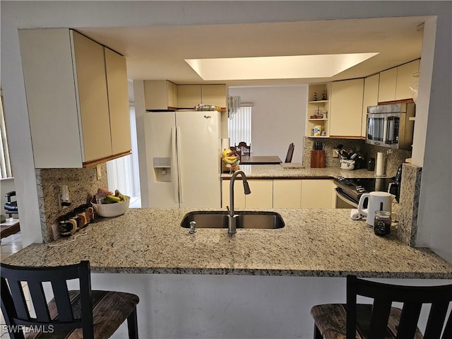 kitchen with backsplash, kitchen peninsula, sink, and stainless steel appliances