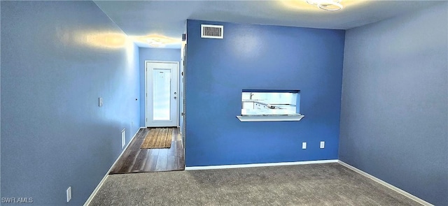 unfurnished room featuring dark carpet