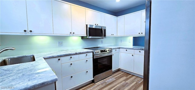 kitchen featuring white cabinetry, stainless steel appliances, sink, and light hardwood / wood-style flooring